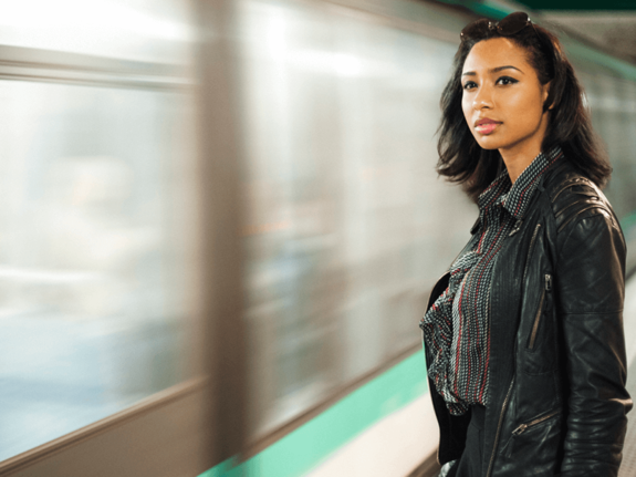 femme à côté d'un métro, le regardant passer