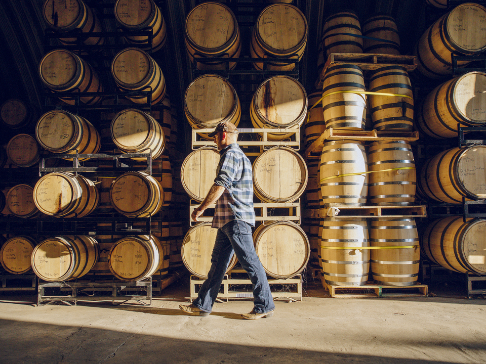 a person standing next to a stack of barrels