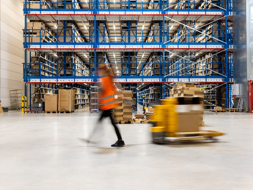 woman pulling on manual forklift in warehouse facility